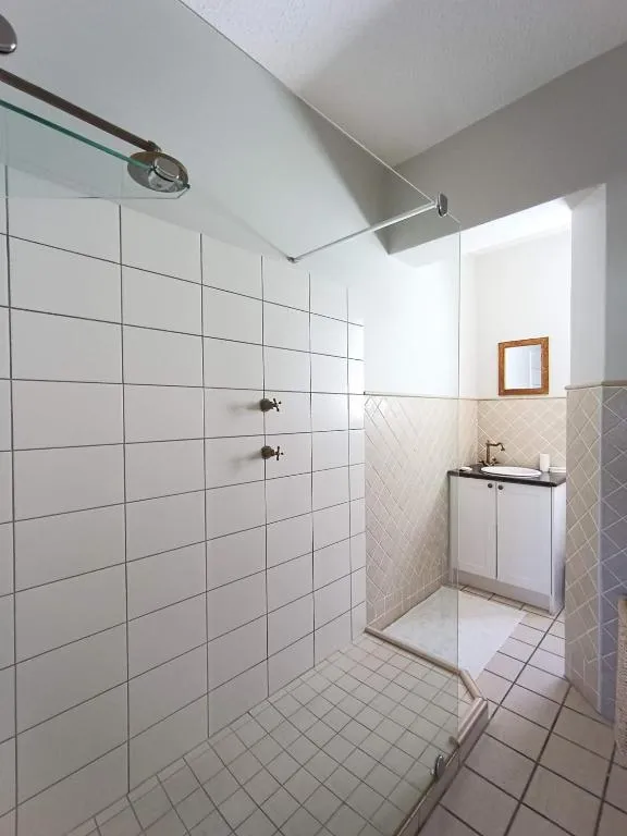 Walk-in shower room with floor-to-ceiling tiling and a separate vanity basin