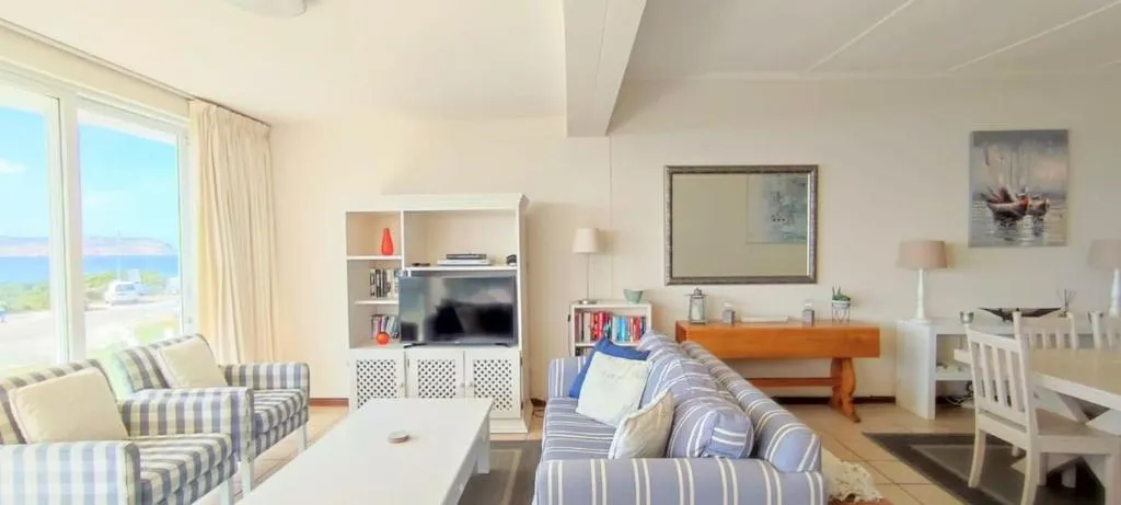 Second living room with striped sofas and floor-to-ceiling windows onto the sea