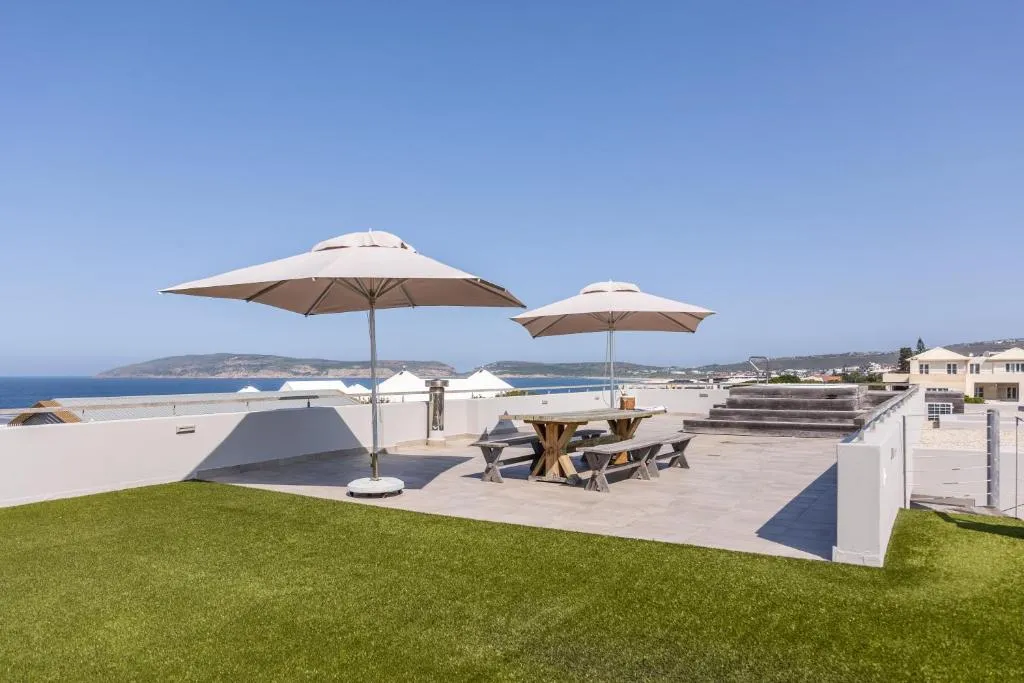 Rooftop terrace with a picnic table, sun umbrellas and artificial lawn overlooking the coastline