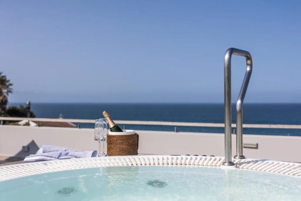 Built-in hot tub on the terrace edge with champagne and glasses, ocean stretching to the horizon