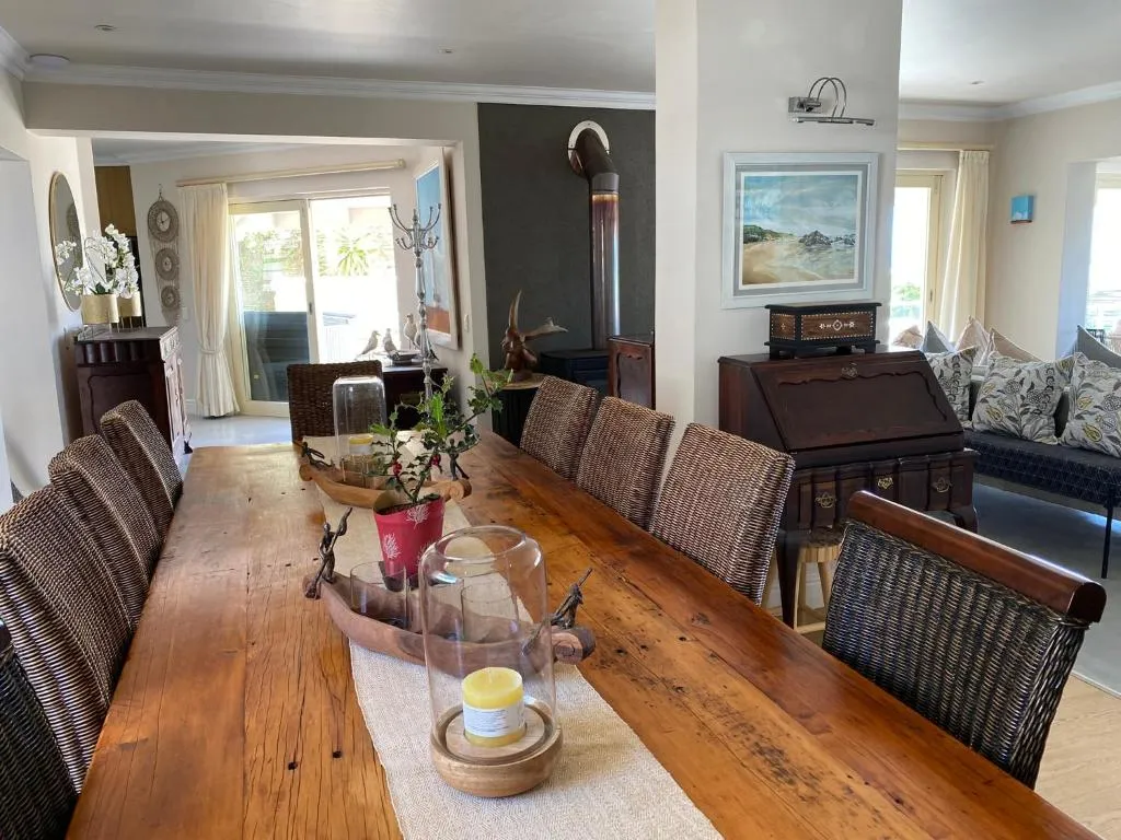 Open-plan dining table for eight beside a built-in wood burner and living area