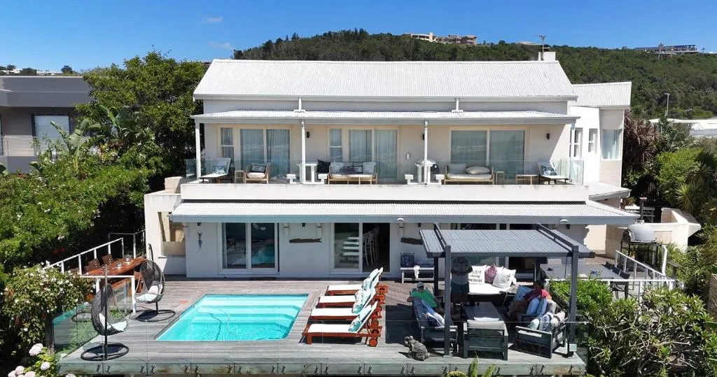 Double-storey house exterior with upper balconies and a pool deck below