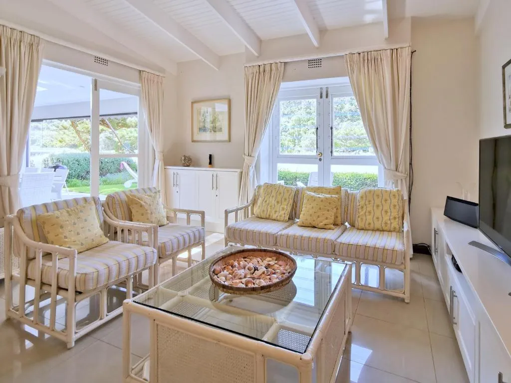 Living room with cream rattan seating, floral cushions and French doors onto the garden
