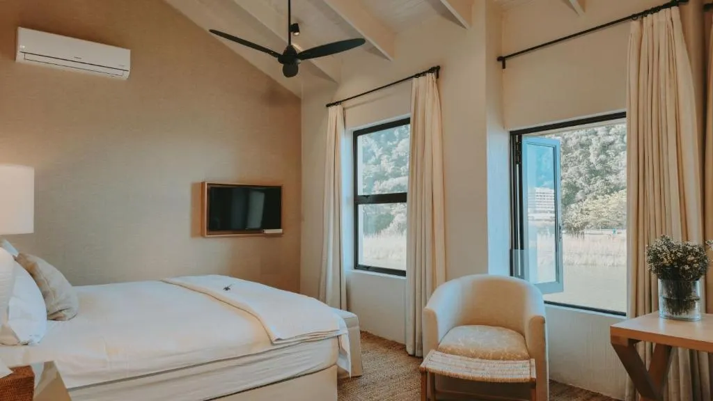 Bedroom with a wall-mounted air-conditioning unit, TV, and windows facing the garden