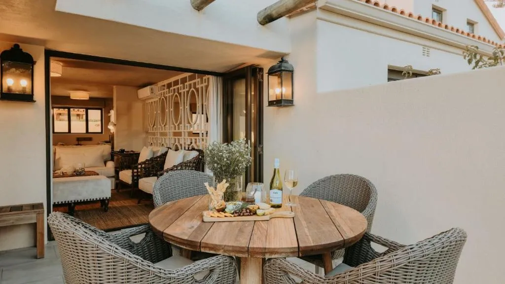 Walled courtyard with a wicker dining table set for four, opening into the living room