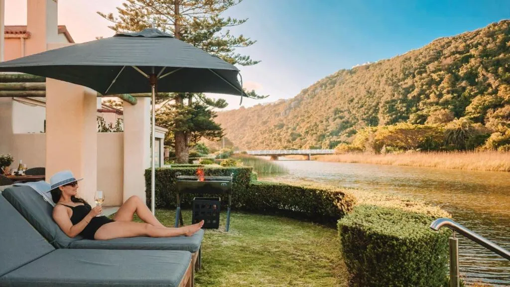 Private lawn with lounge chairs, a market umbrella, and a kettle braai facing the river
