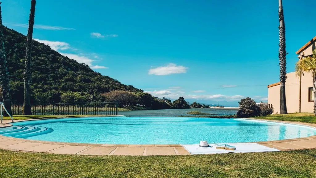 Shared estate pool overlooking the river and hillside, framed by palm trees