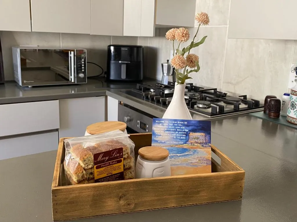 Kitchen counter with gas hob, oven, microwave and air fryer, plus a welcome tray of rusks and flowers