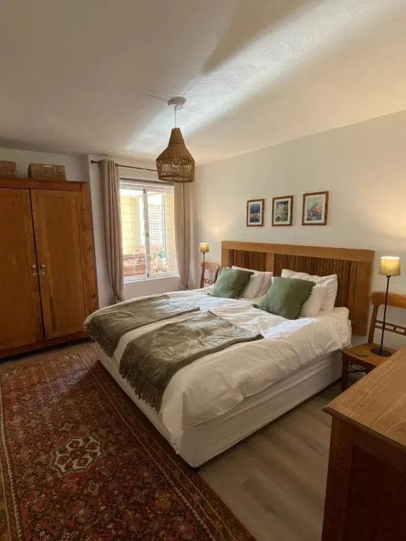 Second bedroom with a carved wood headboard, patterned rug, wardrobe and a window onto a balcony
