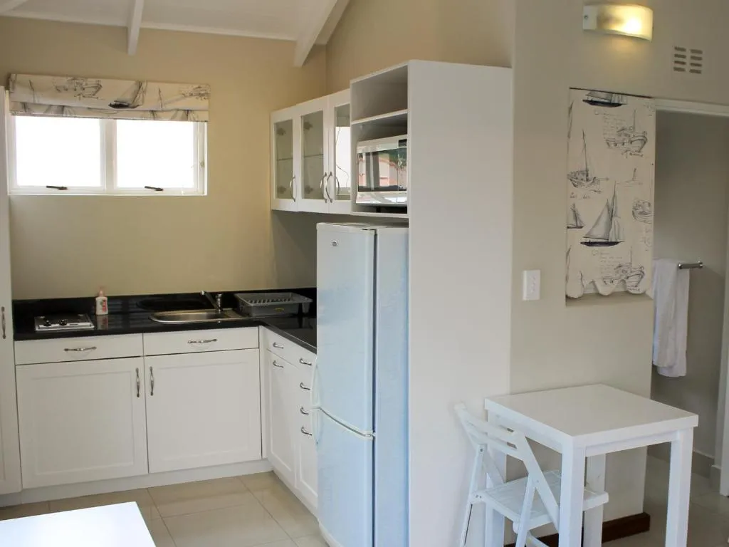 Galley kitchen with black countertops, white cabinetry, a microwave shelf and a breakfast table