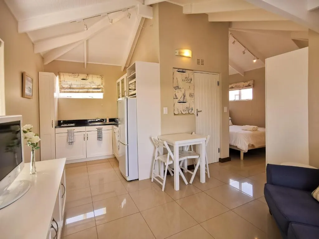 Second view of the open-plan lounge, kitchenette and bedroom doorway with a TV console