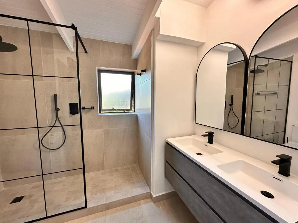 Bathroom with a curbless glass walk-in shower beside a floating double vanity