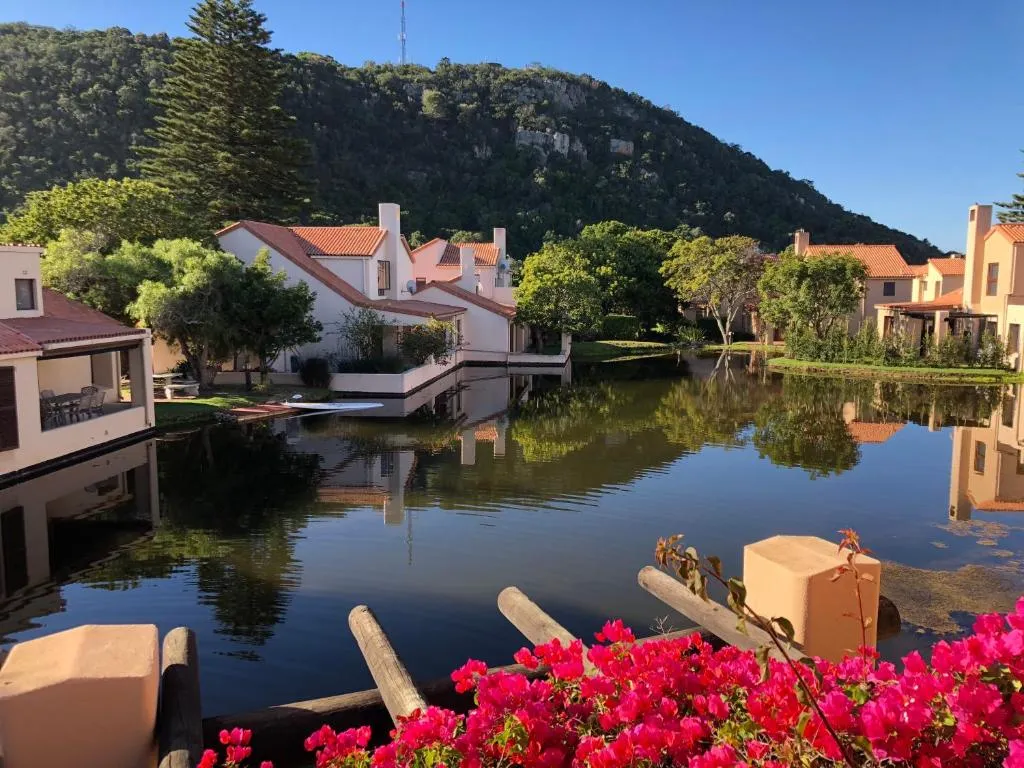 View across the estate's reflective lagoon to terracotta-roofed units and a forested mountain backdrop