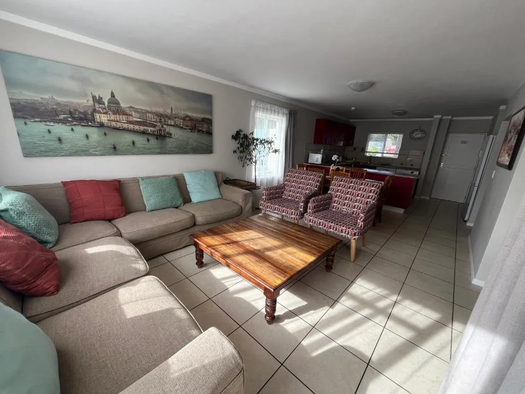 Lounge area opening onto the red-cabinet kitchen, sectional sofa dressed in teal and coral cushions