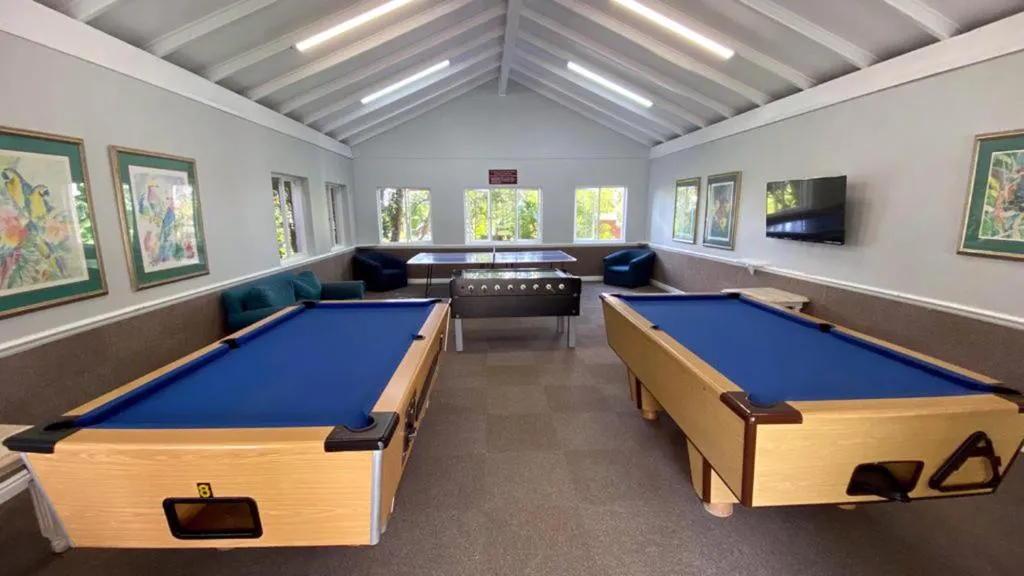 Shared estate games room with two pool tables, table football and a wall-mounted TV