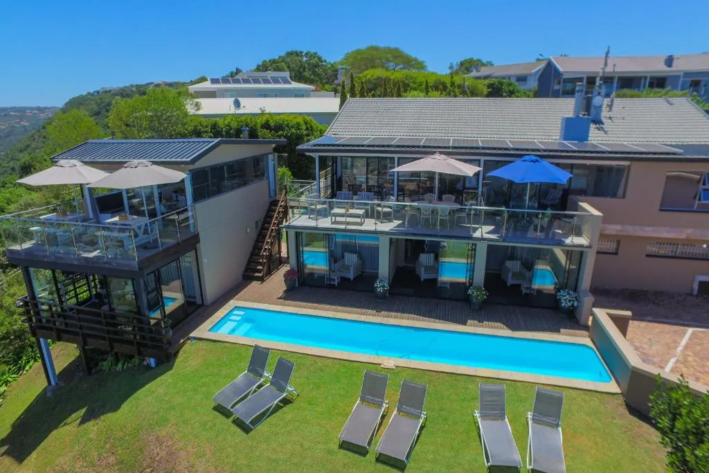 Aerial view of the pool terrace, lawn and multi-level house perched on the hillside above Plettenberg Bay
