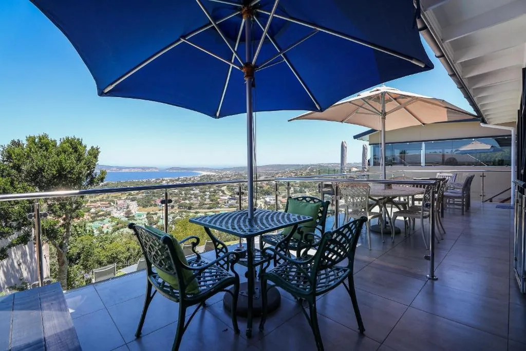 Terrace dining table under umbrellas with a panoramic view across the lagoon to the bay
