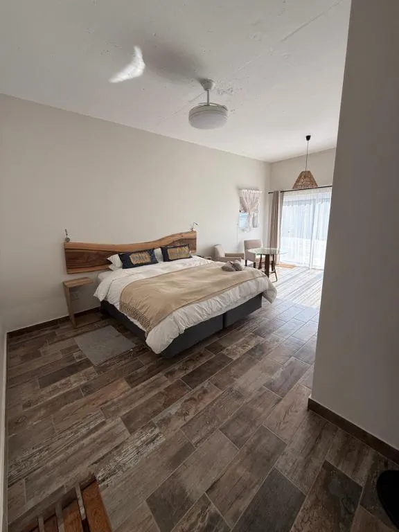 Bedroom with a raw-edge timber headboard and sliding doors onto a private outdoor seating nook