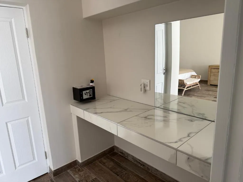Dressing table nook with mirror, in-room safe and a doorway view into an adjoining bedroom