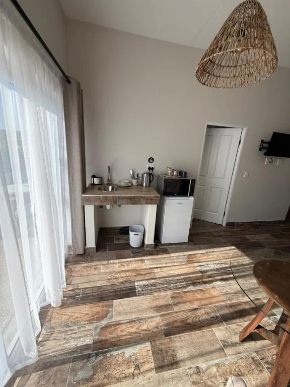 Kitchenette corner with sink, kettle, microwave and bar fridge under a woven pendant light