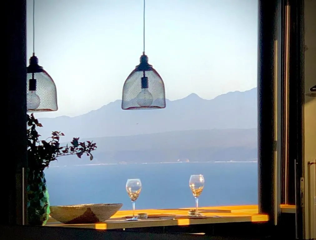 Dining nook beside a window framing mountains and the ocean at dusk, set for two