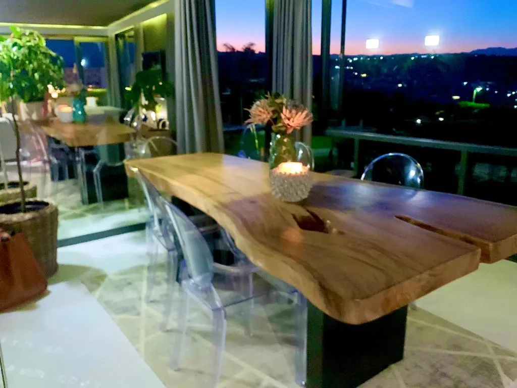 Live-edge wood dining table with candlelight and a night view over the town lights