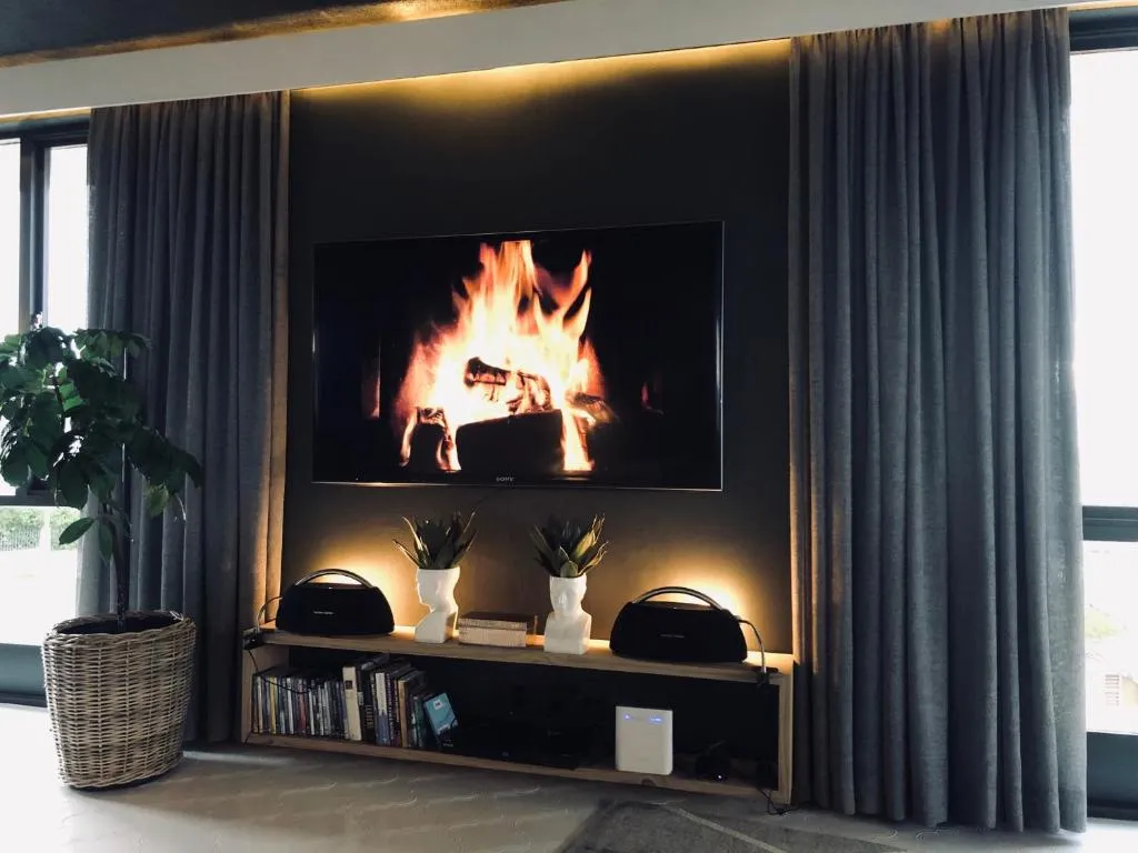 Living room with a wall-mounted screen above a media console flanked by floor-length curtains