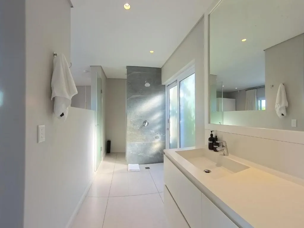 En-suite bathroom with a curbless tiled shower and a long white vanity counter