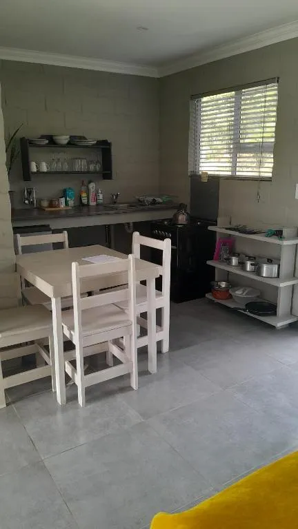 Kitchenette with a dining table for two beside a compact stove and open shelving
