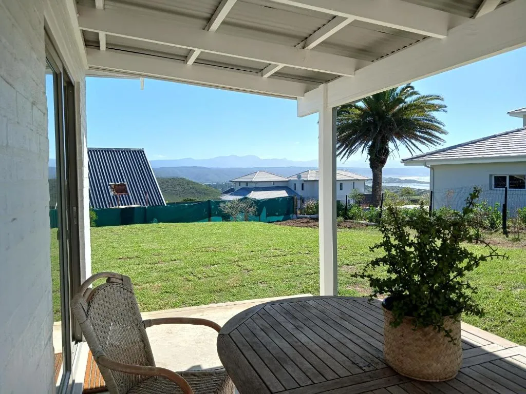 Covered patio looking over a lawned garden to distant hills and a palm tree