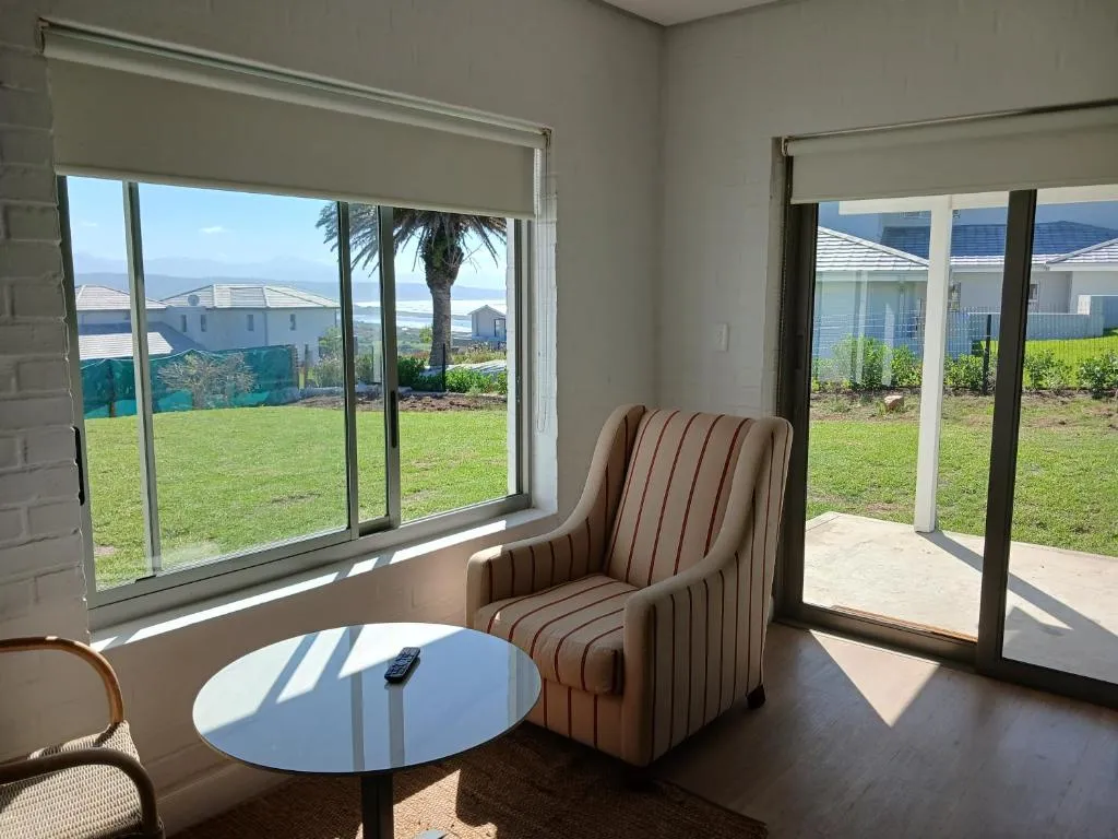 Sitting room with striped armchair and a window looking out to a strip of sea past the neighbourhood rooftops