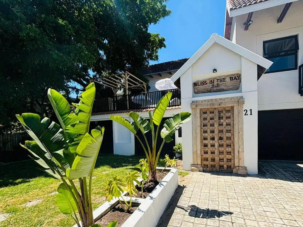 Bliss in the Bay guesthouse entrance with a carved wooden door and tropical garden planting