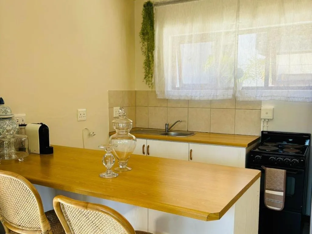 Kitchenette with a breakfast bar, electric stove and sink beneath a curtained window