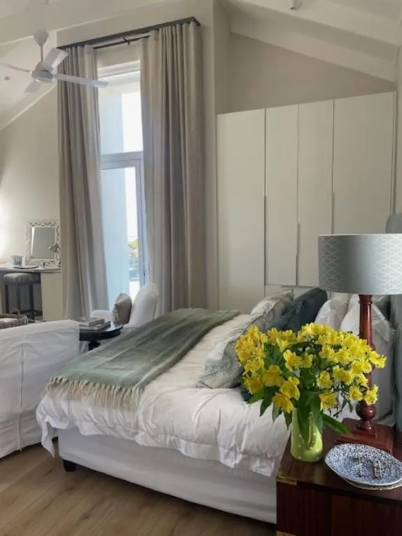 Second bedroom with a vaulted ceiling, floor-length curtains and fresh flowers on the nightstand