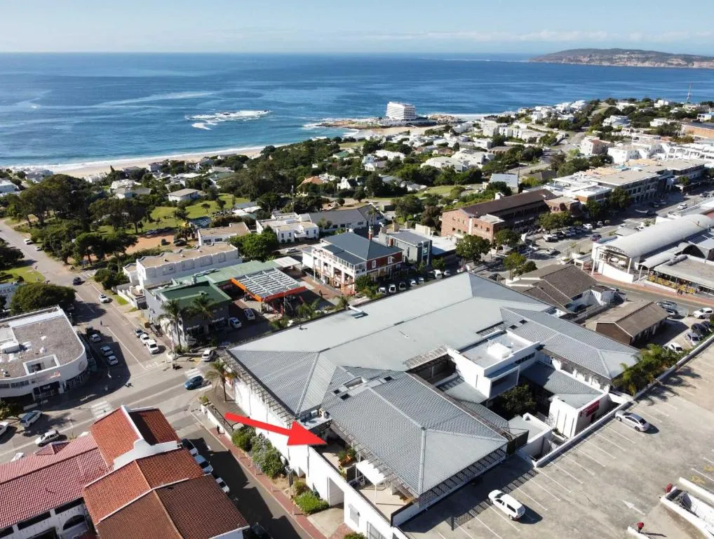 Aerial view of the coastal town with an arrow marking the apartment building's rooftop