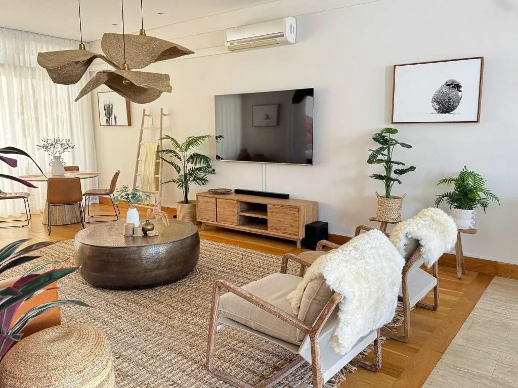 Boho-styled living room with sheepskin-draped armchairs, a wall-mounted TV and air conditioning unit