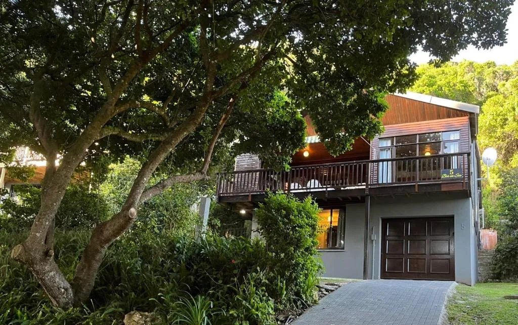 Wooden chalet exterior at dusk with lit windows and a paved driveway
