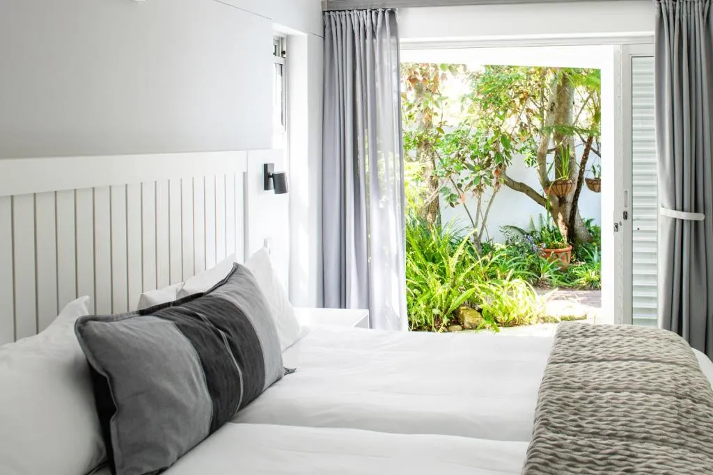 Bedroom with doors opening onto a shaded fern courtyard garden
