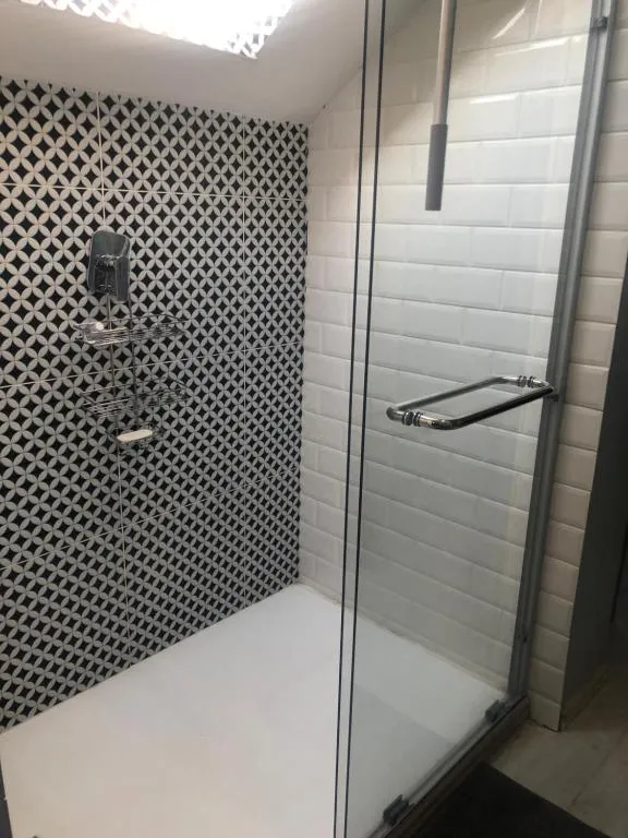 Patterned black-and-white tile shower with a frameless glass screen and rain showerhead