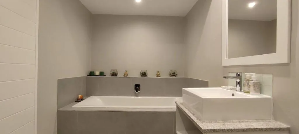 Bathroom with a built-in tub and a separate granite-topped vanity area
