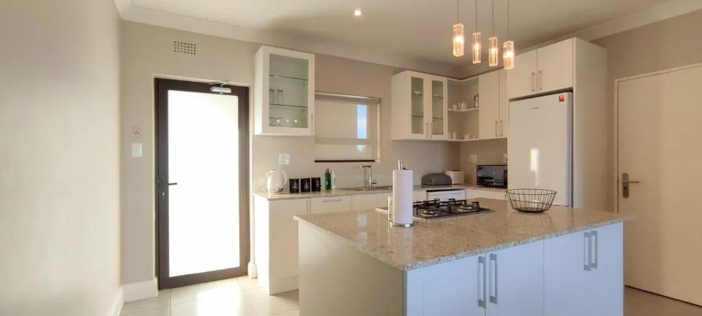 Kitchen with white cabinetry, a granite island and pendant lighting over the counter