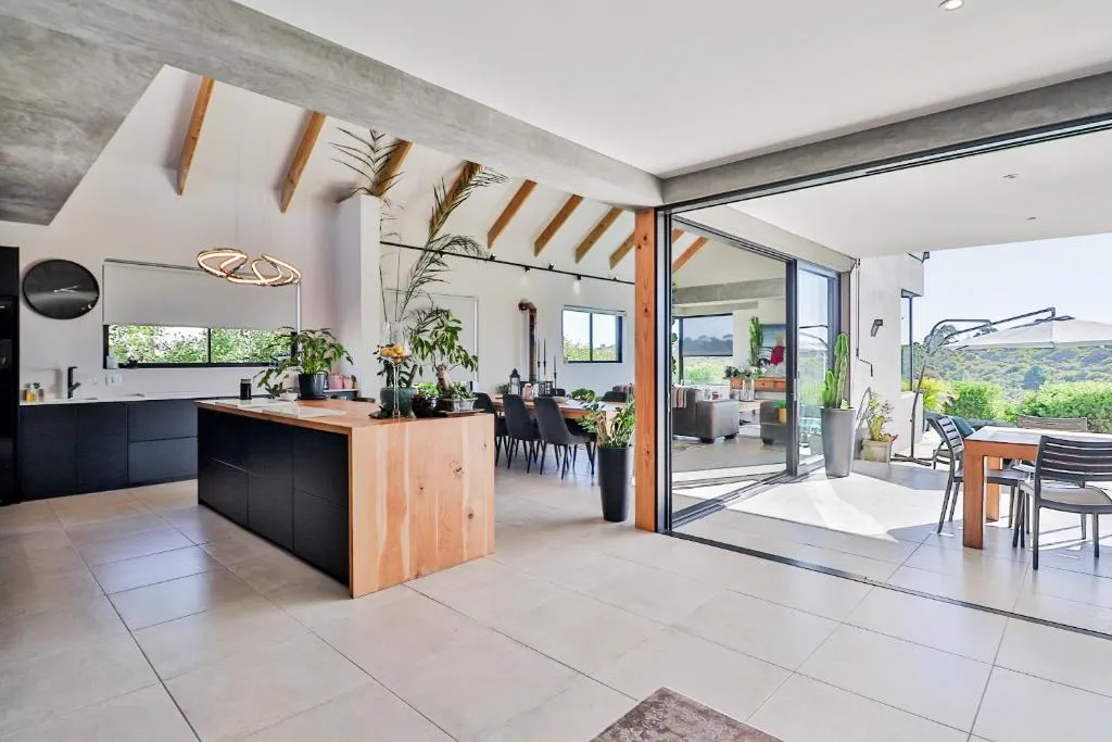 Open-plan kitchen with wooden island opening onto a covered outdoor dining patio