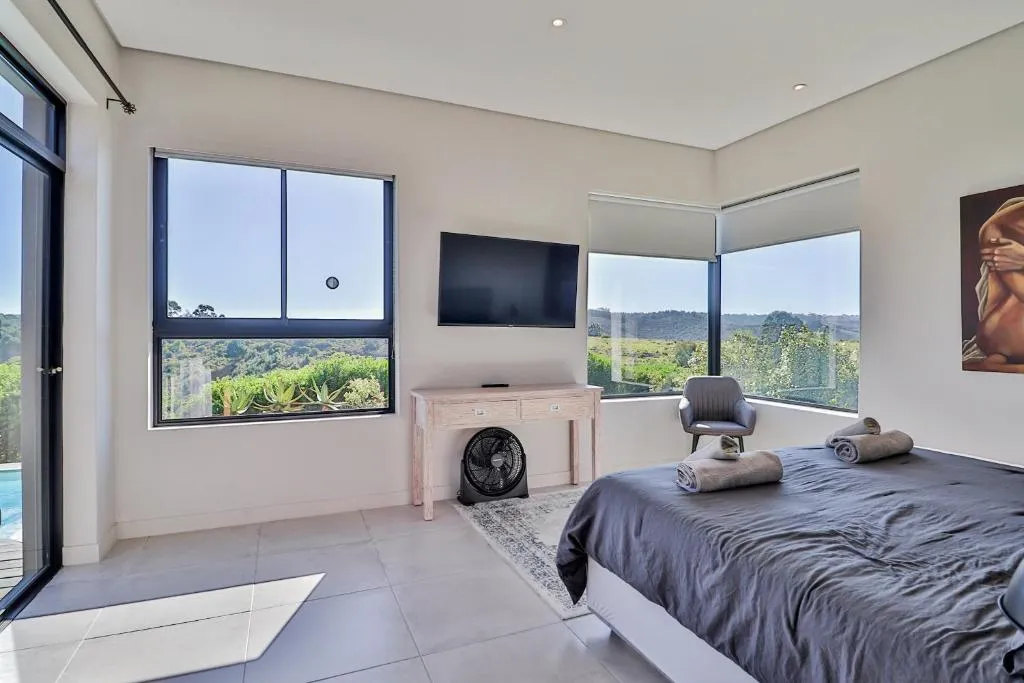 Second bedroom with corner windows overlooking rolling hills and fynbos