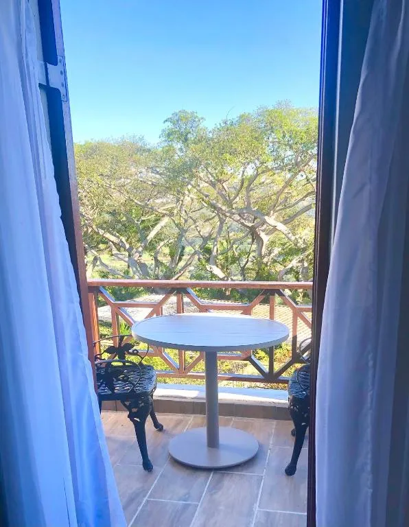 Private balcony with a small table set among tall surrounding trees