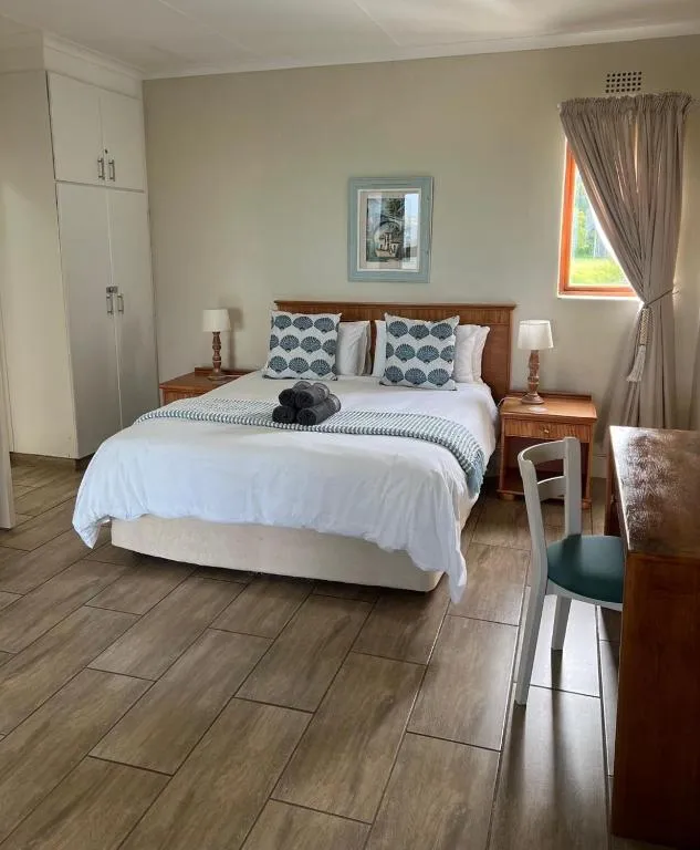 Bedroom with patterned cushions, wooden furniture and a garden-facing window
