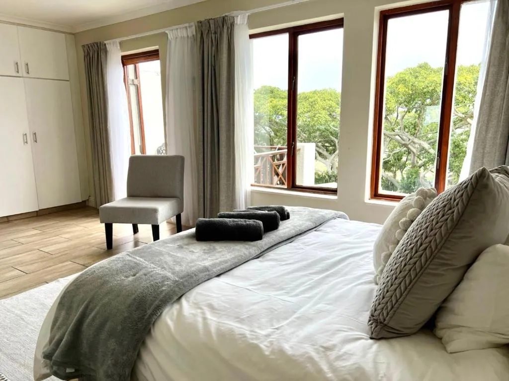 Bedroom with dark wood trim, a wardrobe and windows onto a wooded balcony
