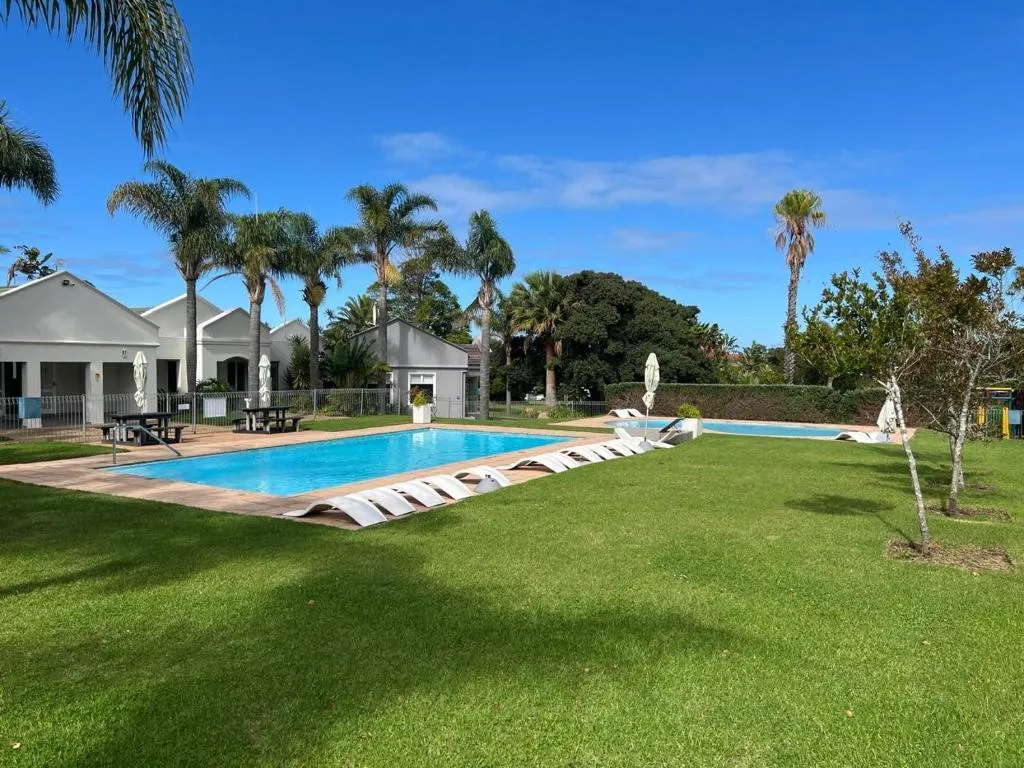 Communal swimming pool on the estate, lined with palm trees and picnic tables
