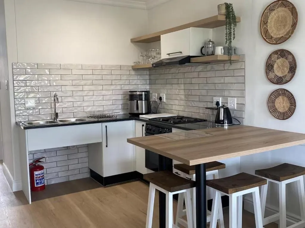 Kitchenette with subway tiles, gas hob and a wooden breakfast bar with three stools