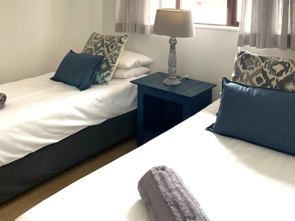 Twin bedroom with two single beds, navy accent cushions and a bedside lamp