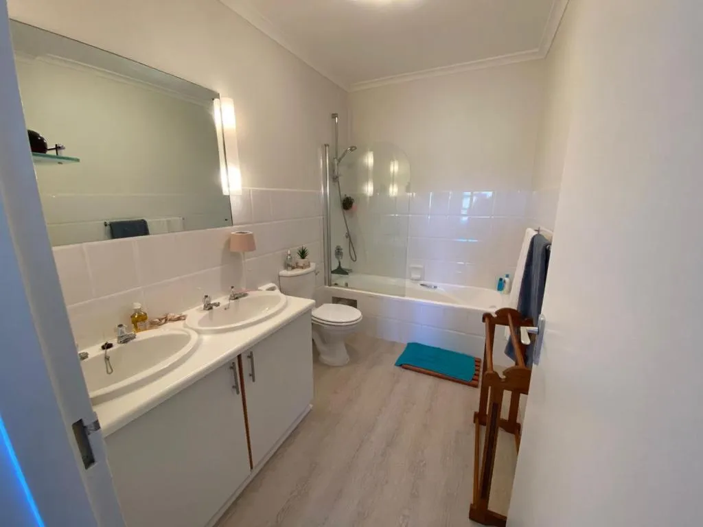 Bathroom with a double vanity, separate toilet and a bath with overhead shower